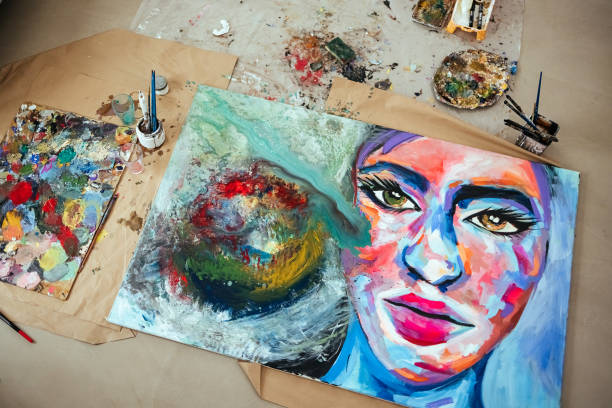 Artist painting canvas using akrylika colors with brushes in bright creative studio