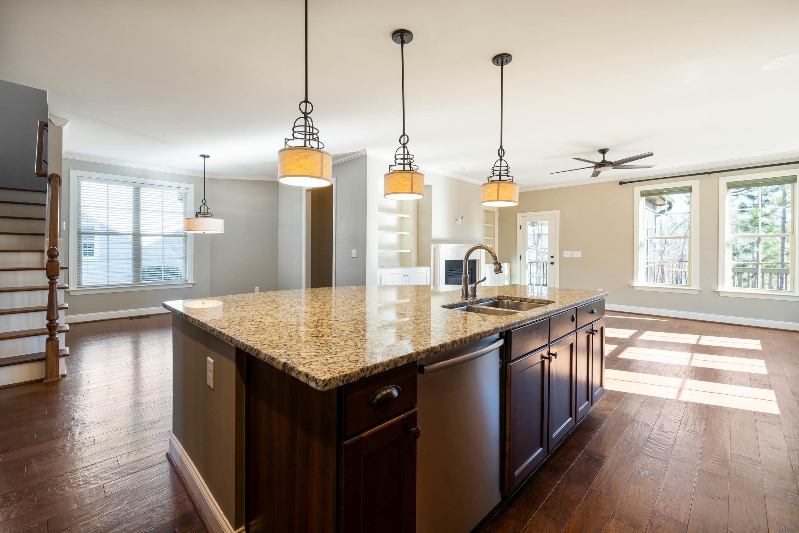 Bright kitchen interior with granite countertop and hardwood flooring.